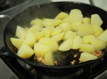 step2: 平底鍋加少許油轉小火放入蒜末拌炒後，放入馬鈴薯塊與蒜末炒香。