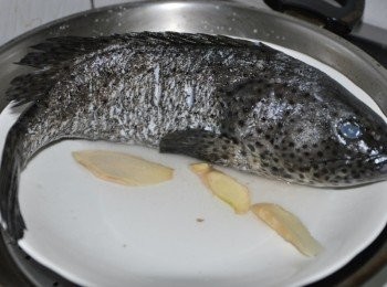 step1: 因為石班比較大尾，所以以大鍋放水蒸魚，將石班解凍後沖洗塗抹少許鹽巴放入圓盤，鋪上薑片，再淋上米酒，大火蒸煮約20~25分鐘(用筷子刺魚肉看有無蒸透)，再起鍋將蒸魚的水倒掉留約1/3米量杯備用