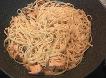 step7: 最後放入義大利麵拌煮到收汁後，即可起鍋擺盤。 義大利麵裝盤後，週邊放上與醬汁ㄧ起煮的鮭魚塊，再把預留的1/3塊鮭魚分切成兩份後放在義大利麵上，擺上新鮮蒔蘿和少許巴西里葉即可。