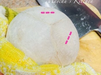 step3: 一手用毛巾將椰皇扶穩，一手用菜刀近手抦那邊的刀角在圖中標示的位置砍出兩個刀口，砍完後插入刀角用槓桿原理一撬，椰皇頂便會呈圓形的裂開。