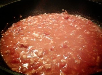 step3: 然後可加白酒，增加香味（可以省略），加罐裝蕃茄，用中火煮沸，加黑胡椒粉及辣椒粉，再用小火煮5分鐘