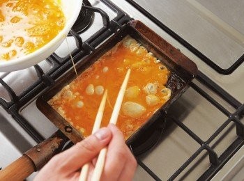 step3: 以中火加熱玉子燒煎鍋，煎熱大量沙拉油，一面以廚房紙巾等吸掉多餘的油分，使沙拉油布滿整個鍋面。加熱至滴入少量蛋汁時會「滋」地烤熟的程度時，便將約1/4的蛋汁倒滿鍋面。