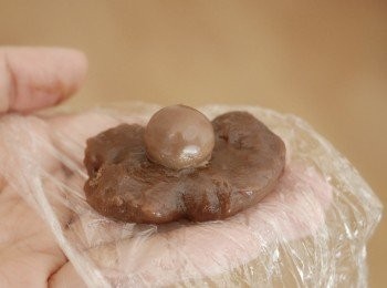 step5: 讓粉團待涼一分鐘，然後戴上膠手套，拿一小份粉團，放一粒朱古力在中間，包好，搓圓