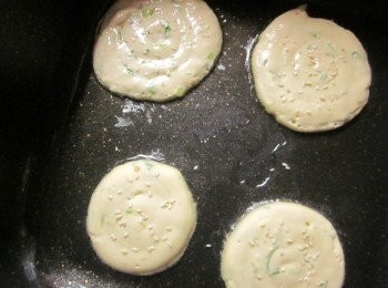 step5: 平底鍋開小火放油及1小匙香油(可省略,加香油煎出來比較香),麵楜由中心點往外繞圈至你想要的大小,趁麵楜未全乾時灑一些白芝麻,以中小火煎到兩面金黃即可起鍋