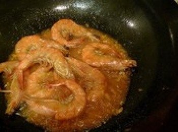 step6: 投入大蝦，沿鍋邊烹入少許料酒、生抽（不能是深色醬油），灑入約3小匙白糖，以炒勺輕壓幾下蝦腦，擠出紅汁，大火炒勻，倒入約小半碗溫水，大火燒開，小火蓋悶