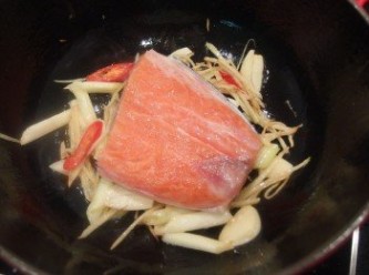 step3: 再將鮭魚放入鍋裡,利用蔥薑蒜鋪在鍋底可防止魚皮黏鍋之外,還可將蔥薑蒜的辛香料之香氣燒入魚肉裡,提鮮去腥。