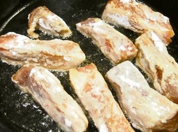 step5: 排骨我用半煎炸的方式。
炸蒜剩下半個飯碗油，倒進平底鍋大約有半厘米深，我就沒有再加油了。排骨裹上生粉，放到熱油中慢火半煎炸至金黃色。如用筷子輕易穿過代表已熟。