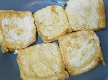 step2: 用廚紙索去豆腐多餘水份，切厚片。落油煎香兩面，舖在碟上。
