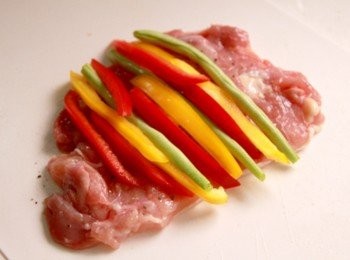 step2: 將雞腿肉內側用刀背略敲並用刀面略拍後灑上少許鹽與黑胡椒。紅、黃甜椒切長條狀。將四季豆、紅甜椒、黃甜椒條放於雞腿肉上，捲起後用牙籤固定接縫處。