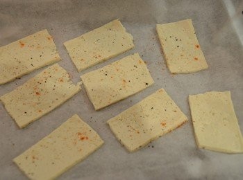 step3: 然後將豆腐片排放在已鋪上烘焙紙的微波盤上，並於豆腐表面撒上適量調味料。