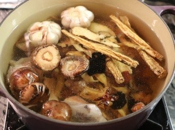 step4: 鍋中加入水，放入清洗好的豬骨、香料包和所有藥材（除了杞子）、香菇和蒜頭。以大火煮滾後加蓋，轉小火煮1小時。