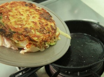 step4: 於鍋面上擺上平盤將鍋翻轉倒出煎餅料後再滑入鍋內將另一面煎熟，同樣方法將餅再度翻轉後於上頭放上培根片翻轉至鍋底將培根片煎香。