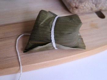 step10: 再用棉繩緊繞兩圈綁結即可。所謂的緊是讓粽葉不鬆掉維持三角形狀即可，若過緊煮的時候可能會爆餡。