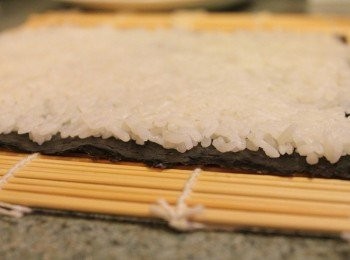 step3: 竹簾上鋪壽司海苔, 約半碗飯的白米盡量壓緊平鋪在海苔上 ** 米飯一定要一邊鋪平一邊壓緊, 壓完的厚度約0.5公分