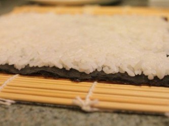 step3: 竹簾上鋪壽司海苔, 約半碗飯的白米盡量壓緊平鋪在海苔上 ** 米飯一定要一邊鋪平一邊壓緊, 壓完的厚度約0.5公分