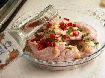 step3: 將雞翅拌入蒜碎、辣椒、38ﾟ金門高梁酒、醬油，用手充份拌勻，蒸盤底部放上香菇塊擺上雞翅，將醃料淋在上頭放入冰箱冷略醃10分鐘，取出放入電鍋中蒸熟。