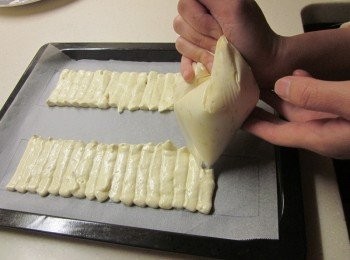 step6: 取一個擠花袋放入擠花嘴,將作法五裝入並按照烘焙紙的範圍擠出麵糊,進烤箱前用篩網灑少許糖粉在麵糊上