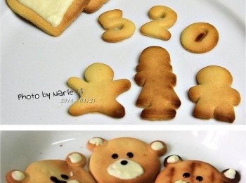 step4: 將烤箱先預熱好，把壓好的模型放在烤盤上即可送進去烘烤 烤至表面呈現出漂亮的色澤就可以了 烤好的小熊餅干待涼用融化的黑白巧克力 為小熊妝扮臉部五官就大功告成了 其實，大面積的白巧克力 我是先隔水軟化後用小湯匙慢慢畫上的 黑巧克力部份我是買有附尖嘴的巧克力醬來使用的 可是我買的是巧克力 (漿)，結果太水了啦！ 不知道巧克力 (醬) 會不會比較稠一些~ 看啊！看吧！！！ 這個《幸福小熊》是不是越看越可愛啊！！！ 我一邊做孩子一邊在一旁搶著吃 幸好這次純粹試驗所以沒做很多的量 不過這餅干的口感又香又酥鬆 實在是很