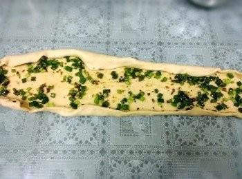 step6: 再把邊邊往裡面捲~再由右住左捲成蝸牛狀~(做到這手有點油)~所以就沒拍了~把麵圑拉長~切成條狀~我喜歡吃絲的口感~切二刀不斷第三刀切斷~共切成4份~把條狀的稍稍拉長~捲成自己喜愛的形狀~這兒其實對我來說是有難度的~因為切開葱花都掉出來了~又有油~所以就一整個不聽話了~所以不管三七二十一了~歪七扭八就歪七扭八了唄~