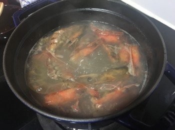 step2: 鑄鐵鍋中倒少量油，將蝦頭及殻倒入炒熟，倒入雞湯及水煲滾。