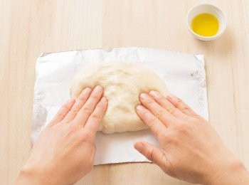 step23: 製作佛卡夏時，在手上沾一點橄欖油（分量外），再將麵團延展成15×10cm的橢圓形。