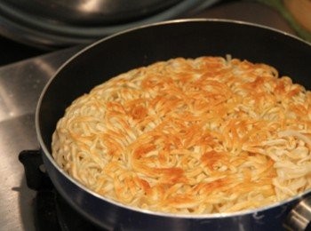 step1: 意麵燙熟瀝乾水份，平底鍋加少許油加熱放入意麵，用小火煎成兩面金黃焦脆，滑入盤中備用。