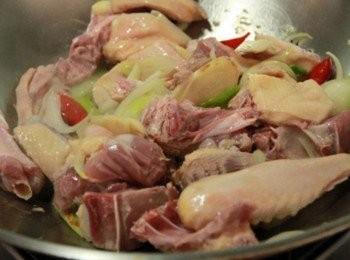 step2: 鍋加油燒熱放入薑片、洋蔥、蔥段、些許辣椒、八角爆香，放入生鴨肉塊拌炒出香氣