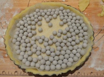 step5: 然後在麵皮上放上一張烘焙紙，放入小烤石壓住派皮底部，以防止膨脹變形。也可用米粒或乾豆類代替。