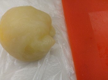 step2: 包芒果糯米糍方法，上下都用保鮮袋夾住粉團,然後用木棒壓成薄皮，包入芒果再將粉皮痴實,將多餘的粉皮切出收口。