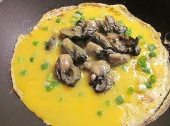 step4: 鍋子洗乾淨重新倒油,油熱加入一半的蛋汁,灑上葱花,中間放入作法3.鮮蚵,再將另一半的蛋汁淋在鮮蚵上,蓋鍋蓋以中小火煎到蛋凝固