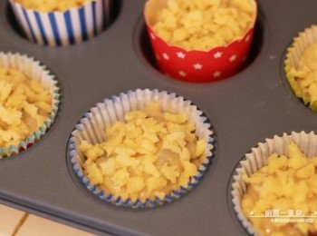 step7: 將麵糊平均倒入杯子蛋糕模中，每份蛋糕分配4個切半櫻桃(即2顆櫻桃的量)，再依個人喜歡的份量鋪上步驟(4)完成的酥粒。