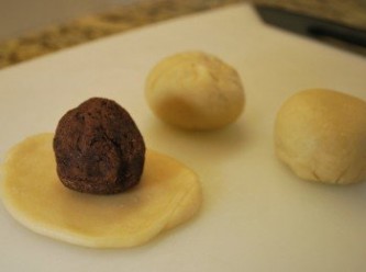 step9: 包餡：取一份麵團桿圓，翻面後光滑面朝下，包覆一份豆沙餡，收口以指尖捏緊