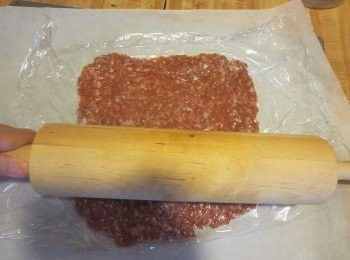 step3: 然後用麵粉棒隔著保鮮紙把肉團擀平至約2mm厚度。