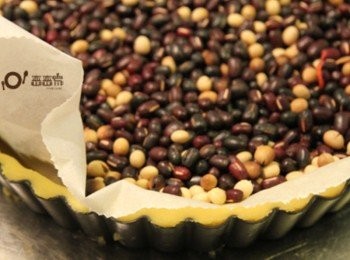 step5: 鋪上烘焙紙，再倒入豆類，送入己預熱170℃的烤箱中烤25分鐘左右自烤箱中取出<span class="group_3">派皮</span>，拿掉豆子和烘焙紙，刷上一層蛋黃液，再送入烤箱烤約10~15分鐘左右