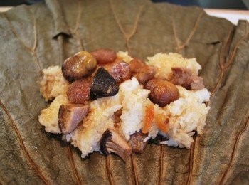 step14: 包粽：將1/8糯米飯置於荷葉中央，塑形成一個矩形，排上適量香菇、滷肉及栗子