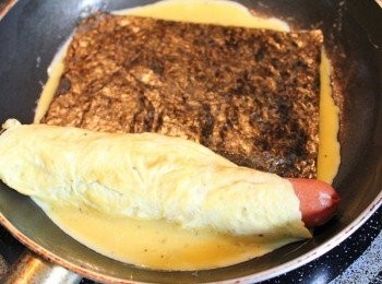 step2: 取小煎鍋, 倒少許油, 開中火. 煎第一層蛋後, 放熱狗捲起, 再倒入第二層蛋汁, 鋪上海苔