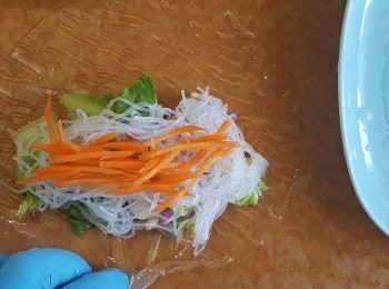 step5: 準備冷開水，將一片米紙放在水上浸2-3秒即取起，備用。依次序放入芒果、生菜、粉絲、<span class="group_2">醬汁</span>、甘荀絲，