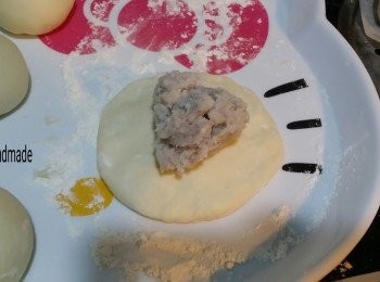 step6: 將麵糰按平，包入芋泥餡，掐實收口位，收口位向下，放上已剪裁成一張細少的牛油紙上面，全部包完之後，穫中放適量的水，放入蒸架，再放入蒸碟，將芋泥包擺上去，擺放每一個包都要預留一些空間，來比它發酵的，用一個噴壺裝少許水，噴少許水在包包面上。