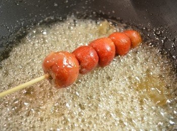 step7: 將山楂串放入糖漿，並迅速轉動竹籤，使山楂均勻地裹上一層薄薄糖漿。