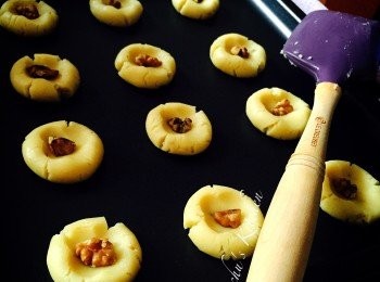 step2: 加入低筋麵粉、梳打粉、食用臭粉及合桃碎，用膠刮拌勻，分成每粒約15g，搓圓及將中間壓凹，放上1/4粒合桃，平均放焗盆上。掃上一層蛋漿，乾面後再掃一層蛋漿。