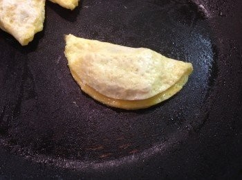 step7: 然後用鏟子挑起蛋皮的另一邊對疊，使蛋皮邊緣黏合，翻面小火煎至兩面金黄色並熟透即可。