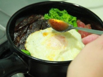 step2: 陶鍋內抹上一層蔬菜油，底鋪上白飯，擺上臘腸、肝腸、芥藍菜、半熟荷包蛋，先淋上少許醬汁，開小火將白飯煎至呈鍋粑狀後再淋上醬汁即完成。