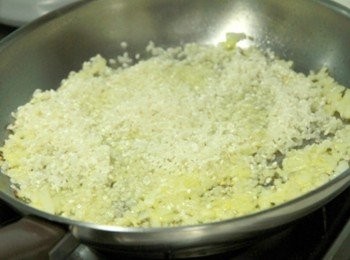 step2: 平底鍋倒入橄欖油加熱，放入洋蔥碎炒至透明狀，轉小火倒入埤南米與洋蔥同炒至米粒呈溼潤感，加入白酒待酒精揮發