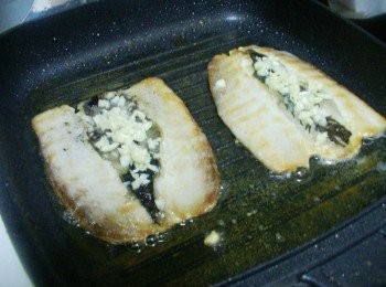 step4: 中火約3~4分鐘後翻面ˊ然後將蒜末夾放在魚肚中