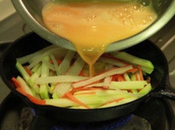 step2: 平底鍋倒少許油加熱，放入蒜末炒香，放入胡瓜絲略炒軟後，加入蟹肉棒絲並倒入蛋液。