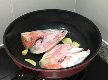 step2: 燒熱油鑊子, 加入薑片爆香後,加入魚頭中火煎香一邊約2-3分鐘, 同時另一邊煲滾水