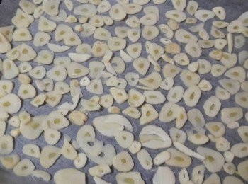 step3: 把切好的蒜片移到已舖好烘焙紙的烤盤上 , 用100度的低溫烤2小時