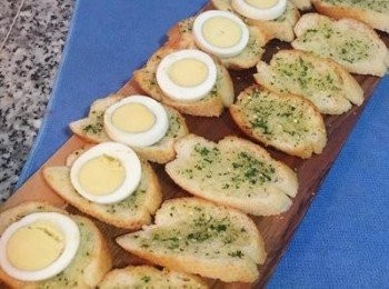 step5: 白煮蛋切片狀備用；鮮蝦用滾水加少許米酒煮熟後去殻切背去泥腸，並用可飲用水洗淨瀝乾備用；法國麵包切片或者吐司切成喜愛的形狀和大小，抹上蒜味奶油醬，烤箱預熱到160度烤5-6分鐘後取出，擺上蛋片。