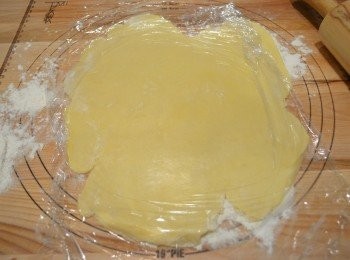 step4: 取一個不黏的8吋菊花派模。工作台上撒一些麵粉，將冰凍好的麵糰放上，鋪上保鮮膜再幹成約 3mm厚，放入模具用手指輕輕壓實，並將多餘的麵皮去掉。