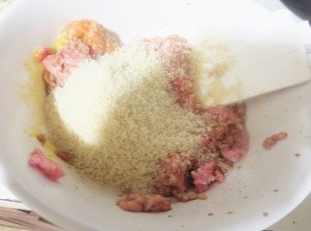 step2: 猪肉馅里磕入一粒鸡蛋。调入生抽、盐、胡椒粉和鸡精，倒入馒头屑。用筷子按顺时针方向充份搅拌上劲；（感觉的到明显的粘性和弹性）